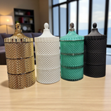 Four decorative jars with textured surfaces and metallic lids on a wooden surface.