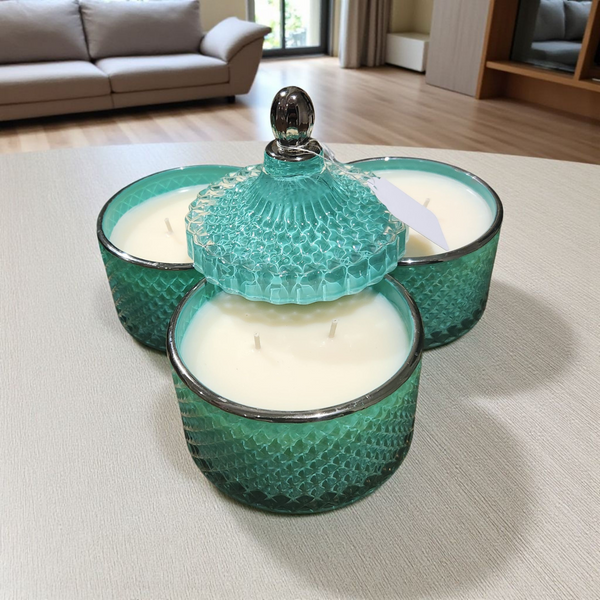 Three green textured glass candle holders with candles on a light surface.